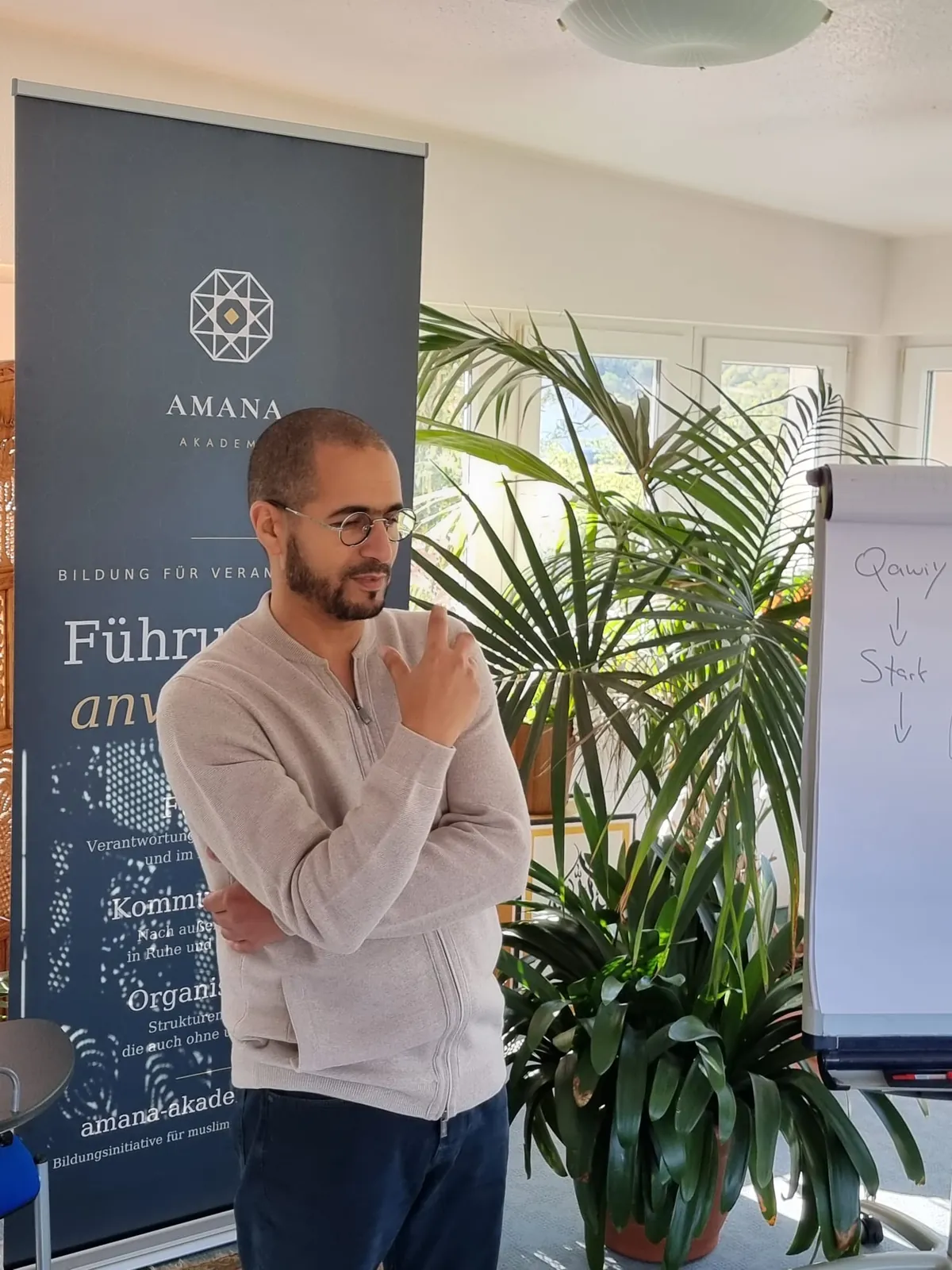 Porträt von Referent Nadir, nachdenklich vor dem Roll-up der Amana Akademie.